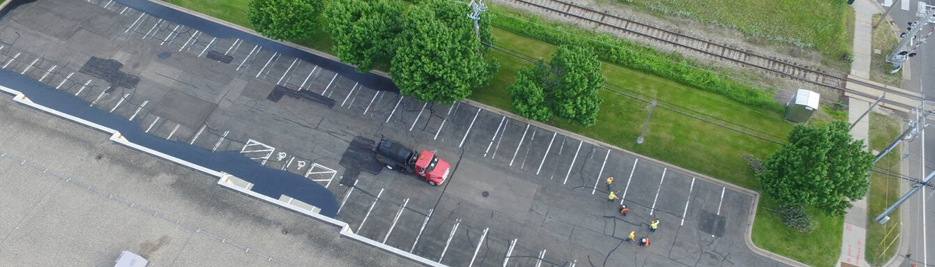 aerial view of asphalt truck and workers repairing parking lot